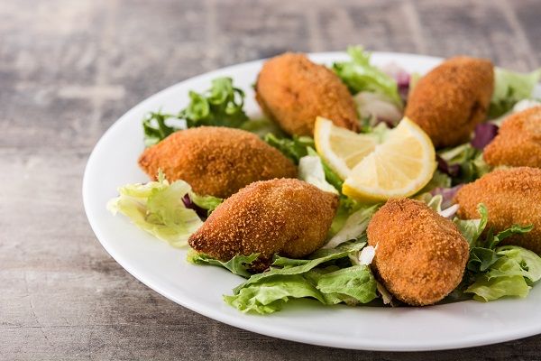 Mejillones tigre rellenos presentados en plato blanco con limón en el centro