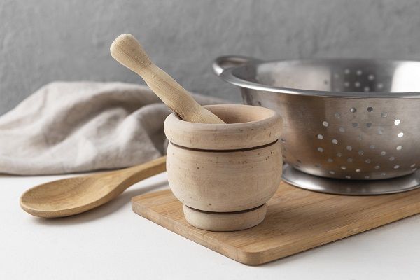 Mortero en la cocina para machacar junto a cuchara y tabla de madera