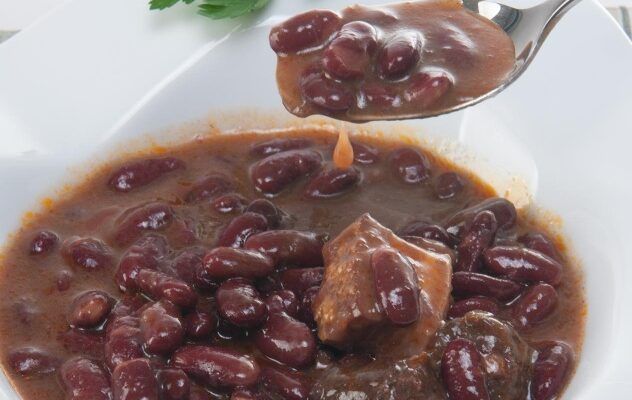 Alubias de Tolosa tradicional con sacramentos presentadas en plato blanco y con cuchara
