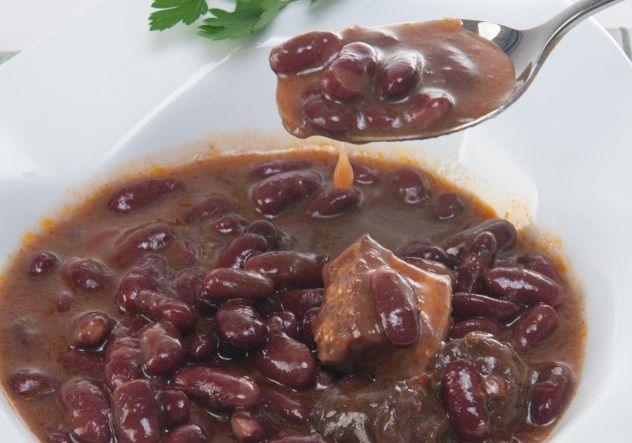 Alubias de Tolosa tradicional con sacramentos presentadas en plato blanco y con cuchara