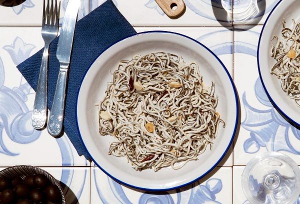 Angulas a la bilbaína presentadas en plato blanco junto a cuchillo y tenedor