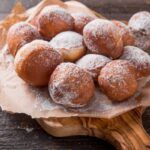 Buñuelos dulces tradicionales presentados sobre papel marrón y tabla de madera