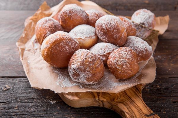 Buñuelos dulces tradicionales presentados sobre papel marrón y tabla de madera