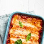 Canelones de pollo con bechamel recién hechos gratinados presentados en bandeja para horno
