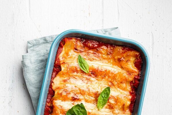 Canelones de pollo con bechamel recién hechos gratinados presentados en bandeja para horno
