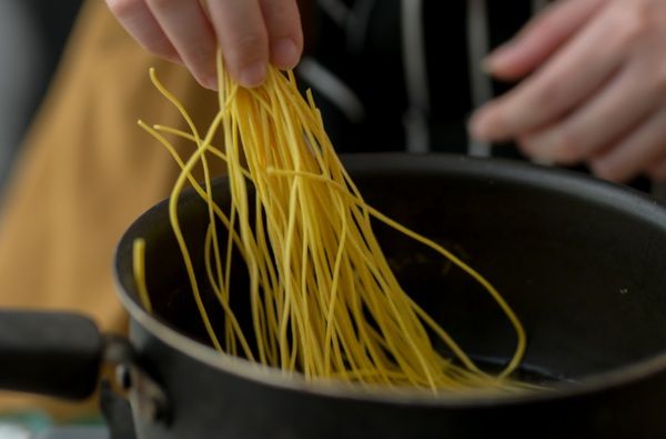 Chef metiendo los fideos en una olla para cocerlos