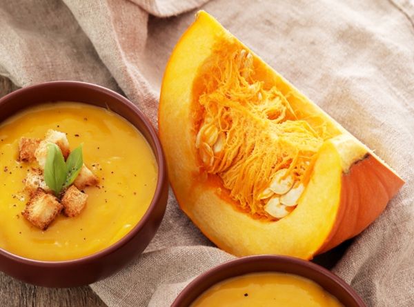 Crema calabaza cremosa casera presentada en cuenco con picatostes y calabaza al lado