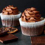 Cupcakes de chocolate presentados en molde de magdalena junto a ingredientes