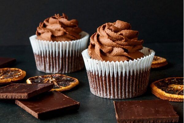 Cupcakes de chocolate presentados en molde de magdalena junto a ingredientes