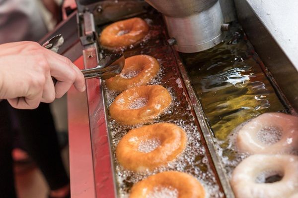 Chef friendo donuts en una freidora