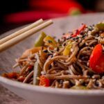 Noodles con verduras en plato blando con palillos de madera japoneses