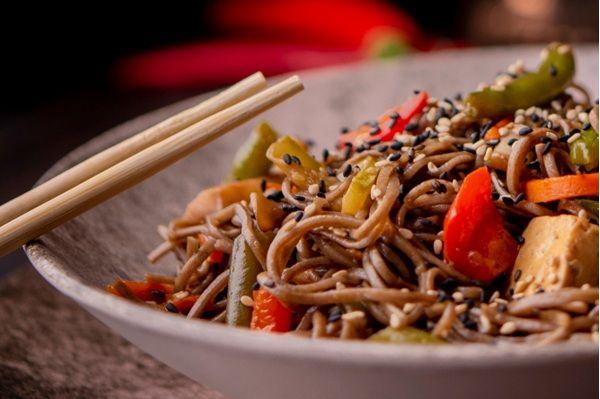 Noodles con verduras en plato blando con palillos de madera japoneses