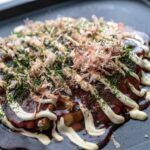 Okonomiyaki presentado en bandeja negra