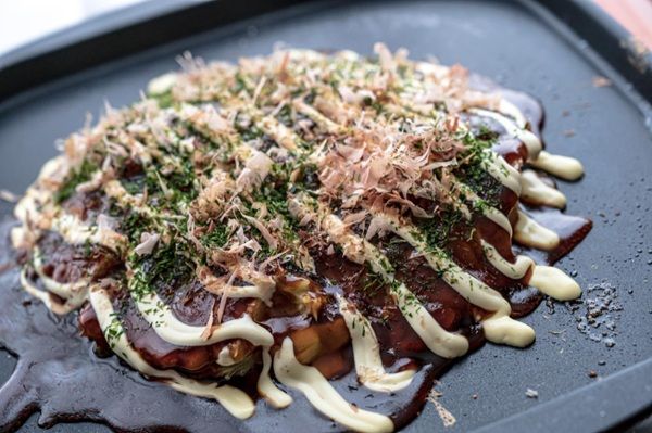 Okonomiyaki presentado en bandeja negra