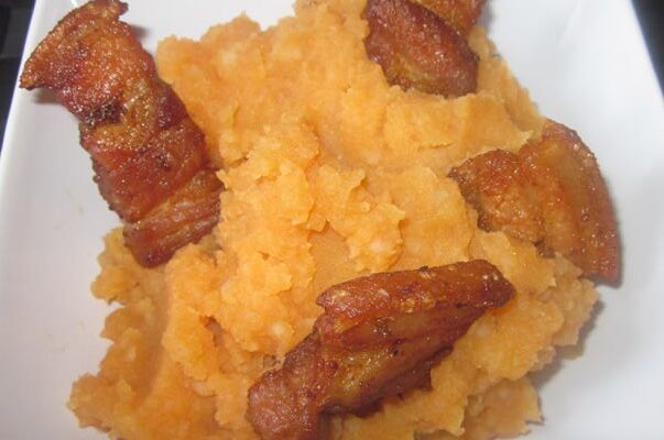 Patatas revolconas con torreznos presentadas en plato blanco