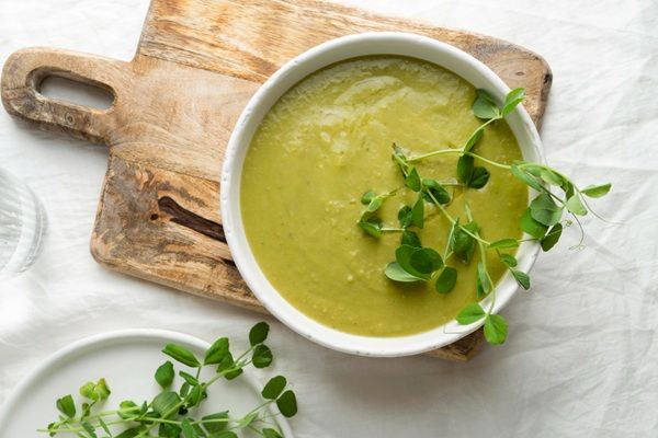 Crema de berros presentada en tazón blanco sobre tabla de madera