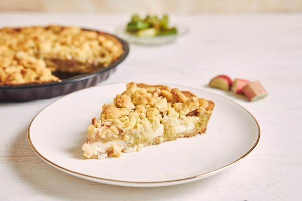 Porción de crumble de manzana en plato blanco y detrás la tarta