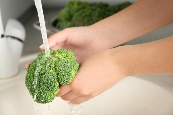 Chef lavando brócoli bajo el grifo de la cocina