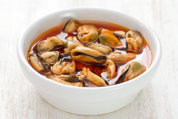 Mejillones cocidos en reposo en escabeche en un cuenco blanco
