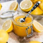 Mermelada de limón en tarro de cristal junto a cuchara y limones