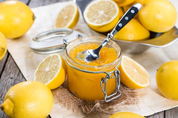Mermelada de limón en tarro de cristal junto a cuchara y limones