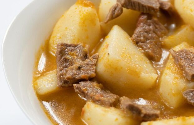 Papas guisadas con carne presentadas en plato blanco