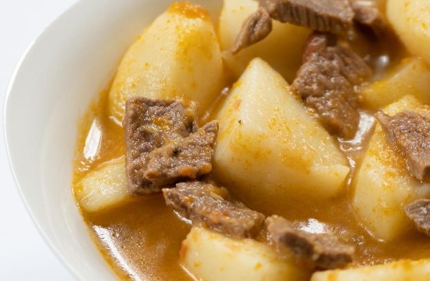 Papas guisadas con carne presentadas en plato blanco