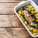 Besugo al horno con patatas presentado en bandeja blanca