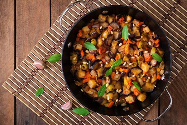 Caponata sicialiana italiana presentada en sartén grande sobre madera