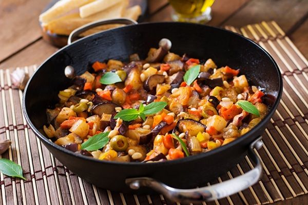 Caponata sicialiana presentada en sartén grande sobre madera