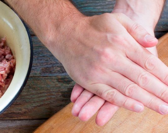 Chef mezclando con las manos la mezcla de carne para formar los filetes rusos