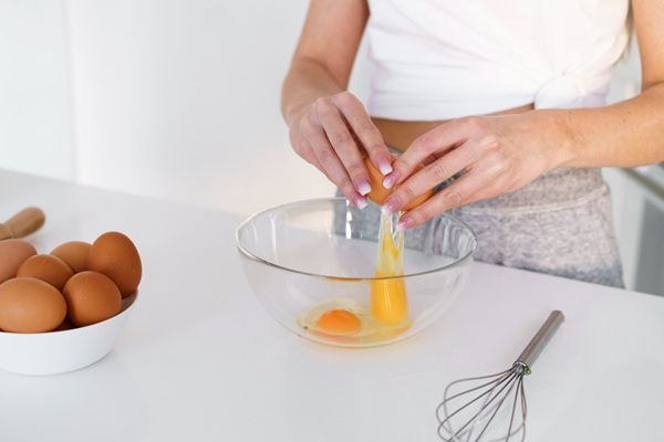 Chef rompiendo huevos en un bol para empezar a batirlos