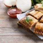 Empanada gallega de carne presentada sobre bandeja y cortada en trozos rectangulares