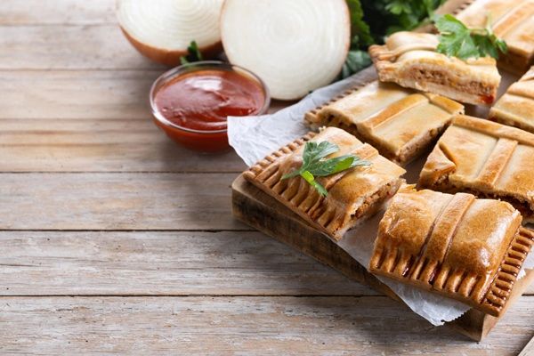 Empanada gallega de carne presentada sobre bandeja y cortada en trozos rectangulares