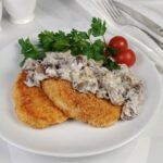 Filetes rusos con champiñones en salsa presentados en planto blanco