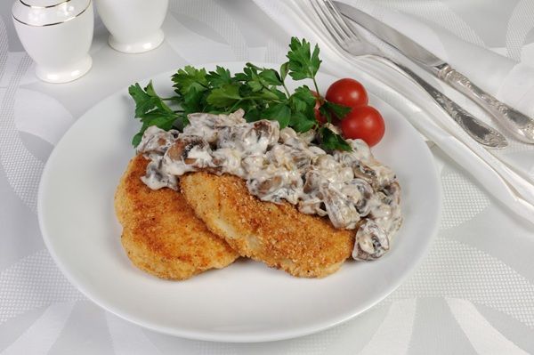 Filetes rusos con champiñones en salsa presentados en planto blanco