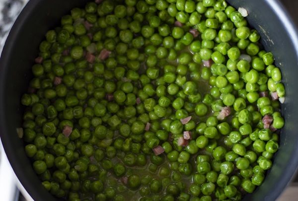 Guisantes con jamón y cebolla de la abuela presentados en una olla