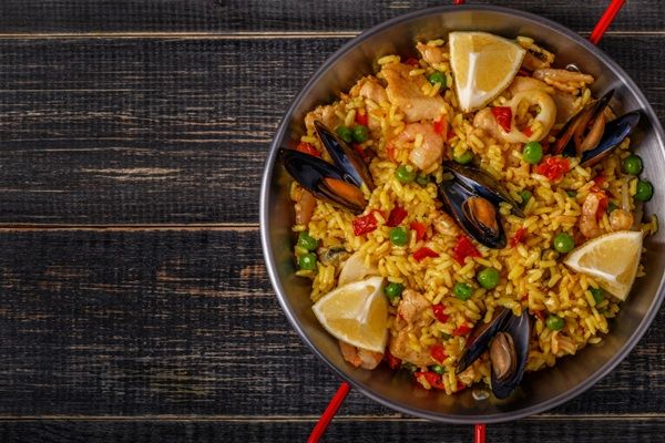 Paella mixta valenciana de pollo y verduras presentada en paellera sobre mesa de madera