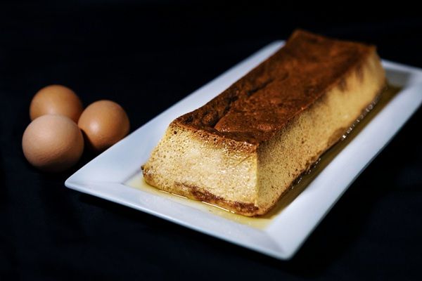 Pan de Calatrava presentado en bandeja blanca rectangular con huevos al lado