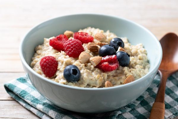 Porridge de avena encima de mantel cuadrado y cuchara de madera