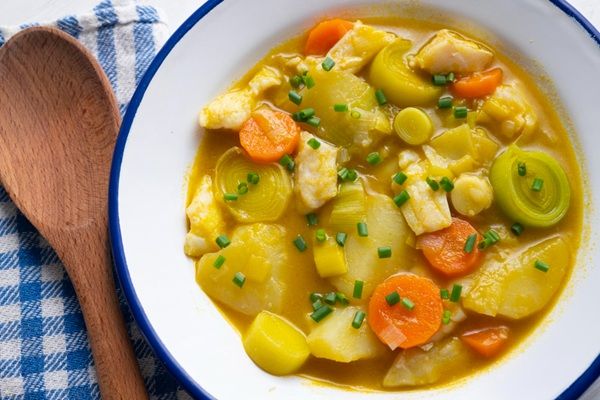 Porrusalda con bacalao presentada en plato hondo sobre paño azul y blanco