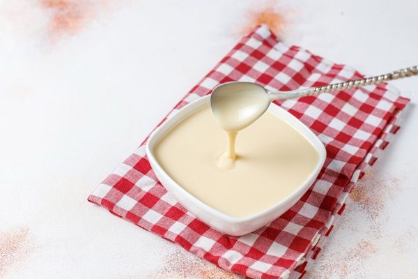Bechamel casera en cuenco blanco sobre paño de cuadros rojos y blancos