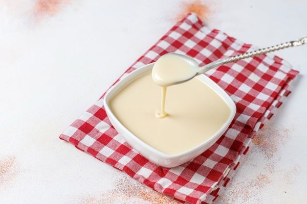Bechamel en cuenco blanco sobre paño de cuadros rojos y blancos