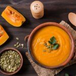 Crema de calabaza presentada en cuenco de barro junto a ingredientes