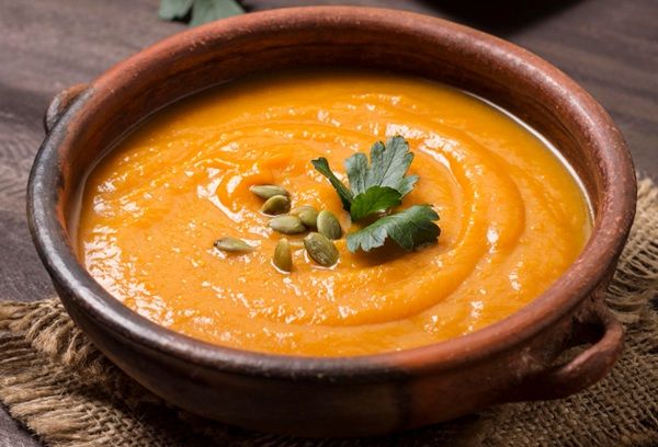 Crema de calabaza presentada en cuenco de barro con pepitas de calabaza peladas