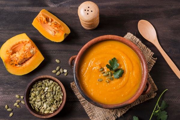 Crema de calabaza presentada en cuenco de barro junto a ingredientes