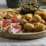 Croquetas de jamón ibérico caseras junto a aceitunas y picos