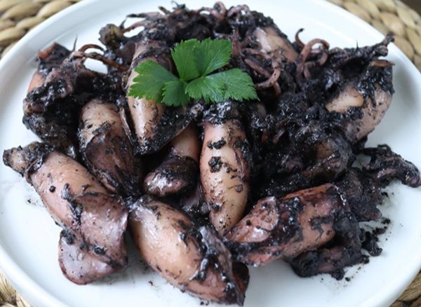 Chipirones en su tinta sobre plato blanco con perejil encima