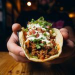 Manos cogiendo delicioso burrito mexicano con carne picada