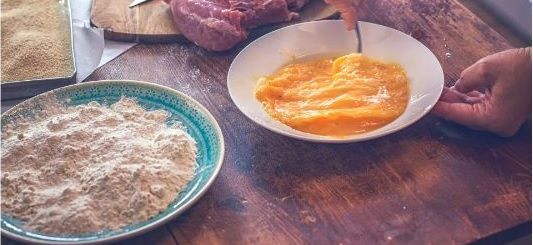 Platos preparados, uno con huevo, otro con harina para hacer el Wiener schnitzel o milanesa de ternera